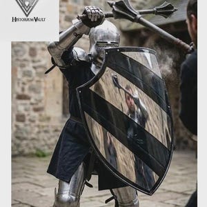 May include: A suit of steel plate armor featuring a polished metal helmet, gauntlets, and leg greaves. A large heater shield with diagonal black stripes is held in front, reflecting the surroundings. A metal mace is raised overhead.