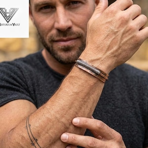 May include: Copper cuff bracelet with a silver-colored spring detail. The bracelet has a hammered texture and is worn on a wrist. The logo for Historium Vault is in the upper left corner.