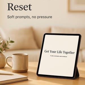 May include: A digital tablet displays the text "Get Your Life Together" on a wooden desk. The tablet is propped up on a stand. A ceramic mug, a notebook, and a small vase are also on the desk. The text "Gentle Guided Reset" is at the top.