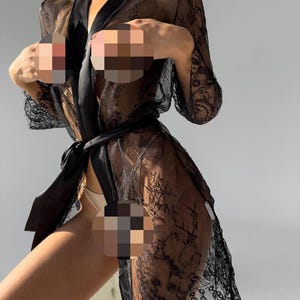 May include: Black lace robe with a satin belt. The robe features a floral lace pattern and long sleeves. The garment is sheer, with a flowing design.