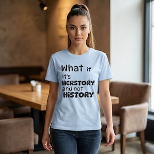 Puede incluir: Camiseta azul claro con el texto negro "What if It's HERSTORY and not HISTORY". La camiseta es de manga corta y tiene cuello redondo. La persona lleva vaqueros azules.
