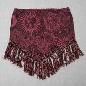 Könnte beinhalten: Burgunderroter und rosa gefranster Schal mit einem himmlischen Sonnen- und Monddesign. Der Schal hat einen dunkelroten Hintergrund mit einem sich wiederholenden Muster aus Sonnen, Monden und Sternen in einer helleren rosa Farbe. Der untere Rand ist mit langen, passenden Fransen versehen.