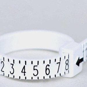 May include: White plastic ring sizer with a measuring tape attached. The ring sizer has numbers 1 through 8 printed on it. The measuring tape has numbers 12 through 18 printed on it.