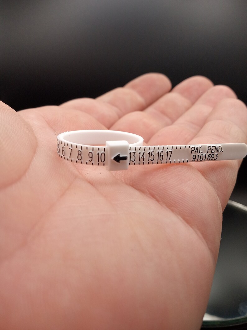 May include: White plastic ring sizer with black markings for sizes 6 through 17. The sizer has a black arrow pointing to the right and the text "PAT. PEND. 9101693".