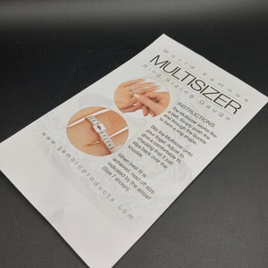 May include: White plastic ring sizer with a buckle and a measuring tape. The Multisizer works like a belt. Simply push the end through the buckle to form a ring shape. Slip the Multisizer onto your finger. Adjust to give a comfortable fit, checking that it just slips back over the knuckle. When best fit is achieved, read off size indicated by the arrow! (Size 7 shown).