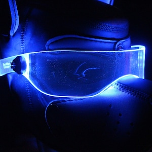 May include: A black leather mask with a blue glowing visor. The visor is clear and has a curved shape.