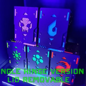 Puede incluir: Una pila de seis cajas negras con diferentes diseños que brillan en la oscuridad. Las cajas tienen una sola bisagra y una tapa extraíble. El texto "SINGLE HINGE VERSION LID REMOVABLE" es visible en la parte inferior de la imagen.