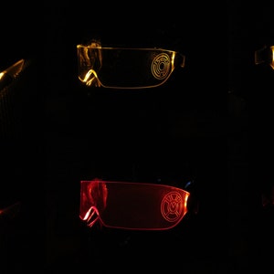 May include: Two pairs of LED light-up glasses, one pair is yellow and the other is red. The glasses have a circular design on the lenses.