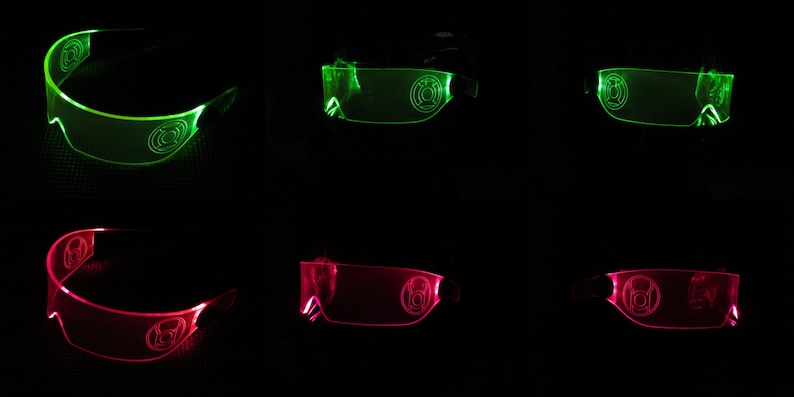 May include: Two pairs of glowing green and pink glasses with a logo on the lenses. The glasses are made of clear plastic and have a futuristic design.