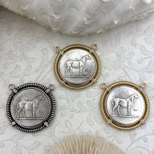 May include: Three circular pendants featuring a relief of a standing horse in the center. Two pendants have a gold-toned twisted wire border with small clear stones, and one pendant has a silver-toned twisted wire border with small clear stones.
