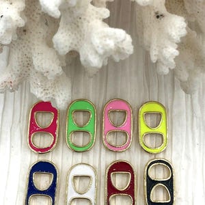 May include: Eight colorful can tab charms with gold-colored trim. The charms are in shades of pink, green, yellow, blue, white, and black. These charms are ideal for jewelry making or other craft projects.