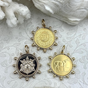 May include: Three gold-colored pendants with intricate designs. One pendant features a detailed emblem, another a crown, and the third a horse. Each pendant has a circular shape with a decorative border and a loop for a chain.