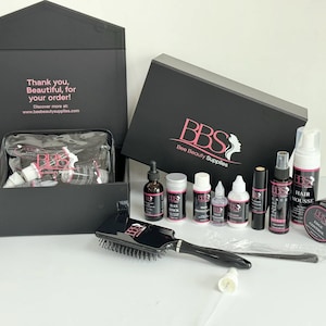 Può includere: Un set di scatole nere contenente prodotti di bellezza, tra cui flaconi, un pennello e una borsa trasparente. La scatola presenta il testo "Thank you, Beautiful, for your order!" e il logo "BBS Bee Beauty Supplies".