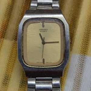 May include: Vintage Seiko Quartz watch with a rectangular gold-toned face and silver-toned metal band. The watch face displays the Seiko Quartz logo and the time. The watch has a classic, retro design.