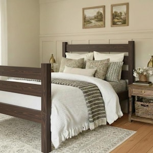 May include: A dark brown wooden bed frame with a horizontal slat headboard and footboard. The bed is dressed with a white duvet, a textured grey and white striped throw blanket, and several decorative pillows in neutral tones and patterns.