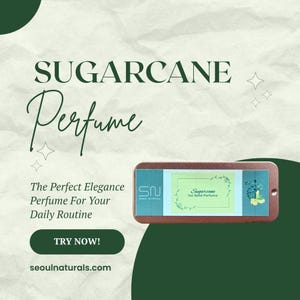 May include: An advertisement for Sugarcane perfume. The image features a rectangular, brown perfume container with a label that reads "Sugarcane 1oz Solid Perfume." The text "SUGARCANE Perfume" is displayed at the top, with additional text promoting the product.