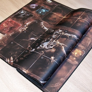 Może przedstawiać: Prostokątna, zwinięta mata do gier z szczegółową ilustracją fantasy. Mata ma ciemną paletę kolorów z obrazami postaci i elementów gry. Krawędzie są czarne, a mata jest częściowo zwinięta.