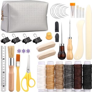 May include: A silver leatherette craft kit with various tools, including needles, thread spools, brushes, scissors, and a ruler. The kit also includes binder clips, a thimble, and a small bag for storage. A comprehensive set for leathercrafting.