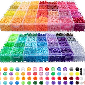 Puede incluir: Dos recipientes de almacenamiento de plástico transparente llenos de cuentas de colores. El recipiente superior contiene tonos de amarillo, naranja, rojo y rosa. El recipiente inferior contiene cuentas verdes, azules y moradas. También se incluyen una variedad de cuentas individuales, hilo y tijeras pequeñas.