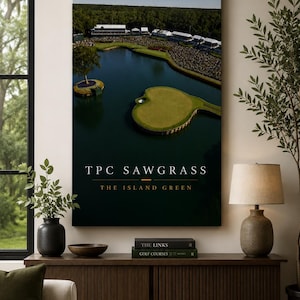 May include: A vertical wall art print featuring an aerial view of the TPC Sawgrass island green golf hole surrounded by water and spectators, with the text TPC SAWGRASS THE ISLAND GREEN printed in white and orange at the bottom of the image.