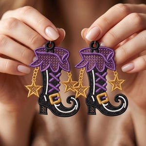 May include: A pair of embroidered earrings shaped like boots with black, purple, and gold thread. Each boot features a purple cuff, purple laces, a gold buckle, and two dangling gold star charms attached by small chains to the top of the boot.