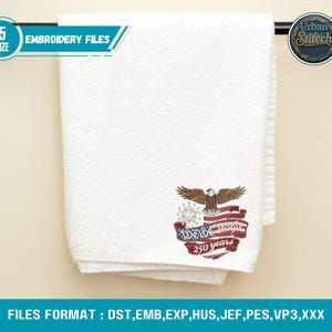 K&ouml;nnte beinhalten: Wei&szlig;es Handtuch mit einem gestickten Design mit einem Adler, der amerikanischen Flagge und dem Text "We the People 250 years." Das Handtuch h&auml;ngt an einem schwarzen Handtuchhalter. Der Text "EMBROIDERY FILES" ist ebenfalls sichtbar.