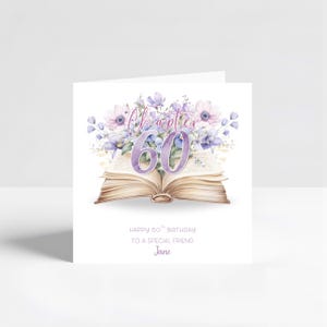 May include: A square greeting card featuring an open book illustration with purple and blue watercolour flowers emerging from the pages. The text reads Chapter 60, Happy 60th Birthday to a special friend, and the name Jane in purple script.