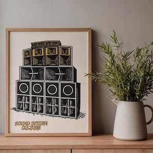 Può includere: Una stampa incorniciata che presenta un'illustrazione grafica nera, bianca e dorata di un sistema di altoparlanti impilati. Il testo "SOUND SYSTEM CULTURE" è stampato in oro in basso a sinistra sullo sfondo bianco sporco all'interno della cornice.