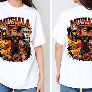 Puede incluir: Camiseta blanca con un gr&aacute;fico de un jugador de f&uacute;tbol con uniforme negro y rojo, con el nombre "MUSIALA" arriba. El dise&ntilde;o incluye la bandera alemana y las palabras "Germany, Rising Star, Elite Technique".