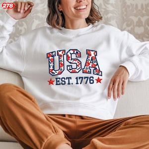 Pode incluir: Uma caneca de cer&acirc;mica branca com uma al&ccedil;a preta e o texto "But First, Coffee" em negrito preto. A caneca est&aacute; sobre uma superf&iacute;cie branca. A caneca tem 10 cm de altura.