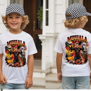 Puede incluir: Camiseta blanca con un gr&aacute;fico de un jugador de f&uacute;tbol, el nombre "MUSIALA" y el n&uacute;mero 10. El dise&ntilde;o incorpora la bandera alemana. El ni&ntilde;o lleva una gorra de b&eacute;isbol a cuadros blancos y negros.