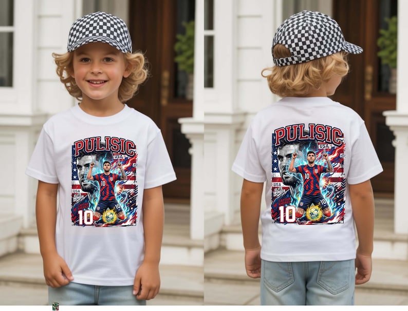 Puede incluir: Camiseta blanca con un gr&aacute;fico de un jugador de f&uacute;tbol y el texto "Pulisic USA 10" en rojo y azul. El dise&ntilde;o incluye una bandera estadounidense. El ni&ntilde;o lleva una gorra de b&eacute;isbol a cuadros blancos y negros.