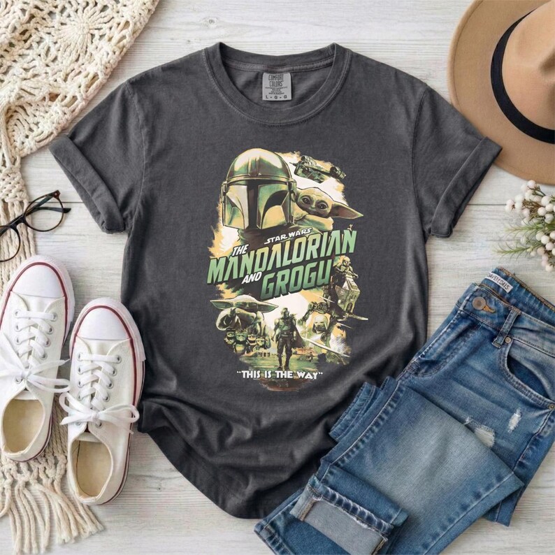 May include: Dark gray t-shirt featuring a graphic from "The Mandalorian" with the text "The Mandalorian and Grogu" and "This is the Way." The design includes images of the Mandalorian and Grogu.