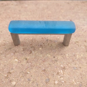 May include: A blue glass cabinet pull with silver metal brackets.