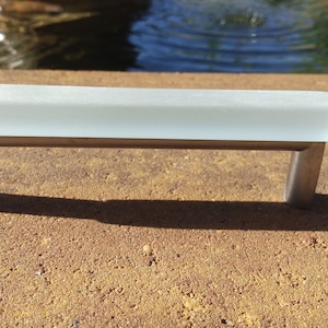 May include: A frosted glass cabinet pull with a brushed nickel finish.