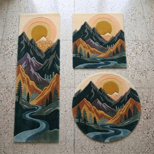 May include: Three rugs with a mountain landscape design. The rugs are rectangular, square, and circular. The design features a river, trees, mountains, and a sun in shades of green, orange, yellow, and blue.