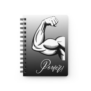 Può includere: Quaderno a spirale con un'illustrazione in bianco e nero di un braccio muscoloso flesso. La parola "Power!" è scritta in corsivo sotto il braccio. Lo sfondo è una sfumatura di grigio.