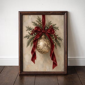May include: A framed wall art print featuring a gold-toned Christmas bauble hanging from a deep red velvet ribbon. The bauble is surrounded by green pine sprigs, small red berries, and gold accents, all set against a neutral, textured background.