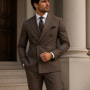May include: A double-breasted brown suit featuring a subtle windowpane check pattern, paired with a crisp white collared shirt, a dark brown patterned necktie, and a matching brown pocket square tucked into the chest pocket of the jacket.
