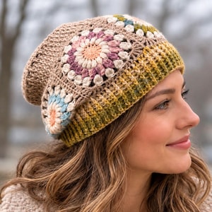 May include: A crochet beanie featuring a tan base with a prominent floral granny square pattern in shades of pink, cream, and light blue. The lower edge of the hat has a ribbed texture in a gradient of olive green and yellow tones.