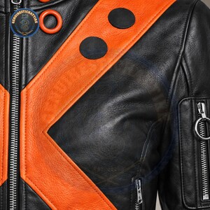 A detailed close-up shot in highlighting the supple, natural grain texture of the black and orange real leather hide, heavy-duty silver zipper track, and two circular black leather patches stitched onto the collar trim.