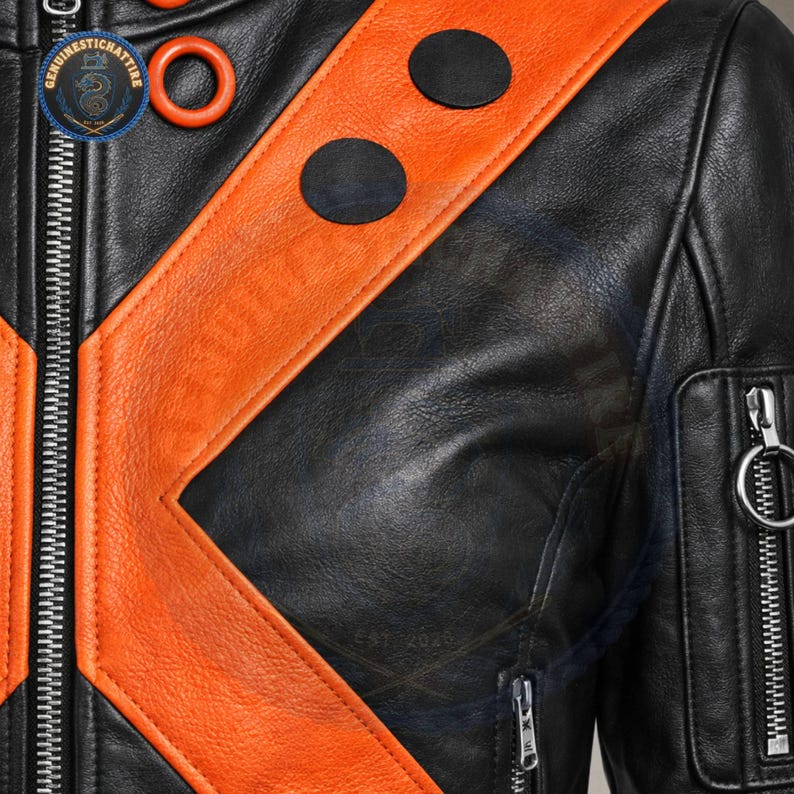 A detailed close-up shot in highlighting the supple, natural grain texture of the black and orange real leather hide, heavy-duty silver zipper track, and two circular black leather patches stitched onto the collar trim.