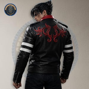Könnte beinhalten: Schwarze Lederjacke mit roter Drachenstickerei auf dem Rücken. Sie hat einen roten Kragen, weiße Streifen auf den Ärmeln und einen Reißverschluss. Getragen mit dunkler Jeans.