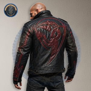 May include: Black leather jacket featuring a red tribal design on the back. The jacket has a quilted pattern on the shoulders and sleeves. The model is wearing blue jeans. The jacket has a zip closure and a stand-up collar.