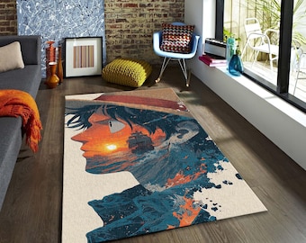 May include: A rectangular area rug featuring a profile of a character with a straw hat, set against a sunset and ocean backdrop. The rug's design incorporates shades of blue, orange, and beige, creating a vibrant and artistic aesthetic. The rug is placed on a wooden floor.