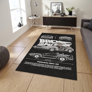 May include: Black rectangular rug featuring a DeLorean DMC-12 blueprint design with the text "BACK TO THE FUTURE". The rug has a detailed illustration of the car and technical drawings.