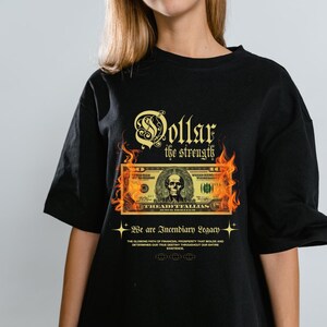 May include: Black t-shirt with a graphic of a dollar bill on fire, with the words "Dollar the strength" above. The text "We are Incendiary Legacy" is below the dollar bill graphic.