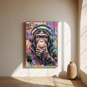 Può includere: Una stampa artistica da parete rettangolare raffigurante uno scimpanzé che indossa grandi cuffie. Il primate ha una mano appoggiata vicino al mento. Lo sfondo è una vibrante esplosione di schizzi di vernice in stile graffiti con il testo MUSIC SOUL.