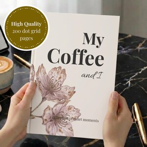 Puede incluir: Un cuaderno blanco con el texto My Coffee and I, a collection of quiet moments, y una ilustración floral. Una insignia circular indica High Quality 200 dot grid pages. La portada presenta dos flores de color marrón claro a la izquierda.