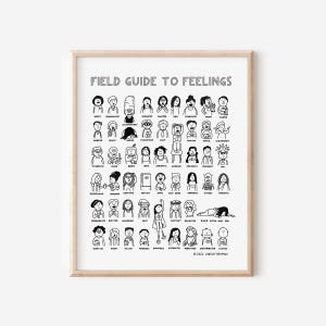 May include: A framed print titled "FIELD GUIDE TO FEELINGS" features a grid of black and white cartoon illustrations depicting various emotions. The artwork includes text and is set against a white background, framed in a light wood.